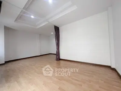 Spacious empty room with wooden flooring and elegant ceiling design