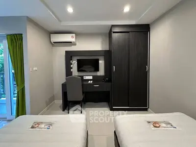 Modern bedroom with twin beds, desk, and balcony access in a stylish apartment.