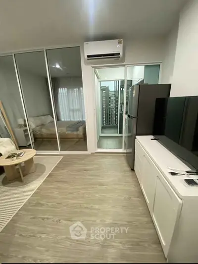 Modern apartment interior with open living area and bedroom, featuring sleek design and natural light.
