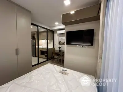 Modern bedroom with sleek design, featuring a large bed, built-in wardrobes, and a flat-screen TV, leading to a well-appointed dining area.