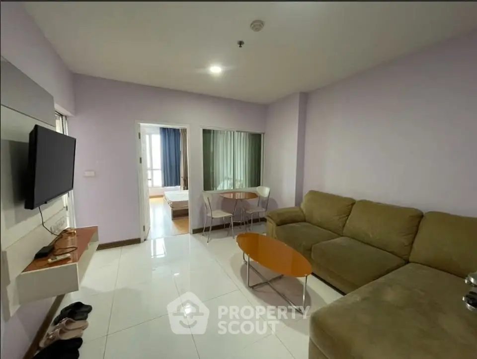 Spacious living room with modern furniture and wall-mounted TV in a cozy apartment.