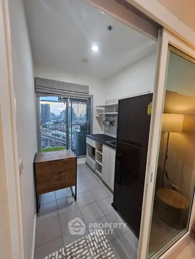 Compact kitchen with modern appliances and city view from balcony