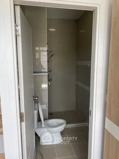 Modern bathroom with sleek tile design and compact layout, featuring a shower and toilet.