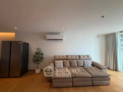 Spacious living room with modern sofa and air conditioning, perfect for relaxation.