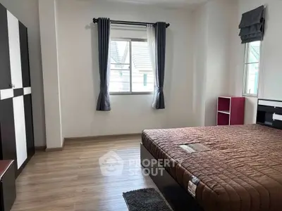 Spacious bedroom with modern furnishings and large window for natural light.