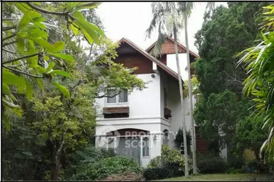 Charming multi-story house surrounded by lush greenery and tall trees, offering serene living environment.