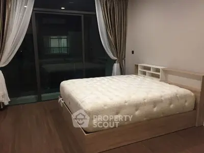 Spacious bedroom with large bed and modern decor, featuring floor-to-ceiling windows and elegant curtains.