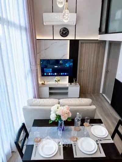 Modern living room with high ceiling, elegant dining setup, and stylish decor in a contemporary apartment.