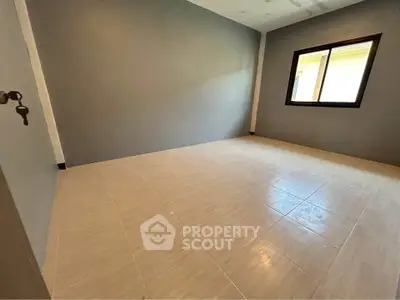 Spacious empty room with large window and tiled flooring, perfect for customization.