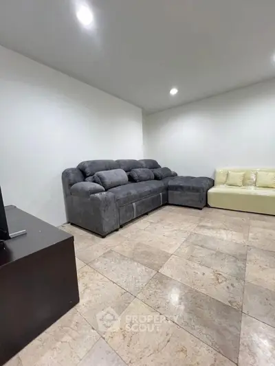 Spacious living room with modern gray sectional sofa and tiled flooring