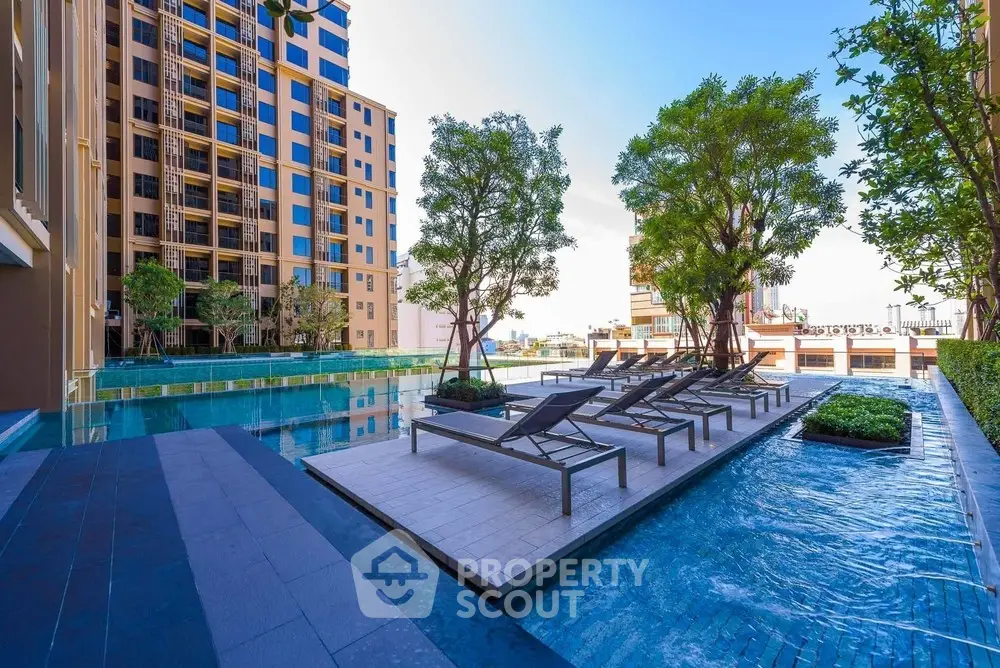 Luxurious apartment complex with stunning pool and sun loungers, perfect for relaxation.