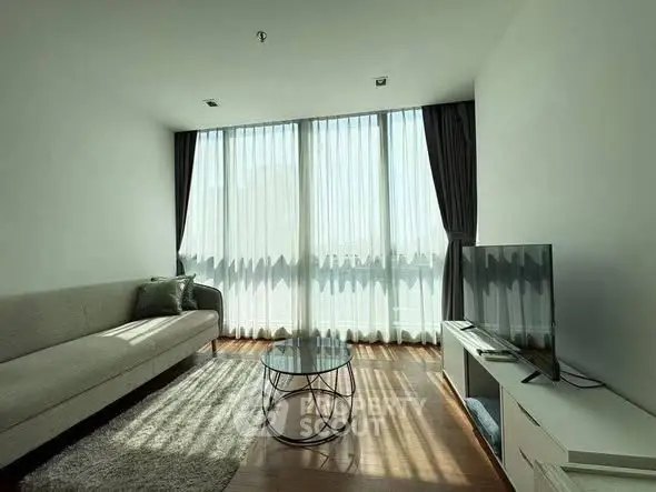 Modern living room with large windows, sleek furniture, and abundant natural light.