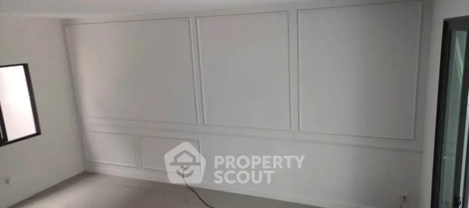 Spacious unfurnished room with elegant wall paneling and natural light