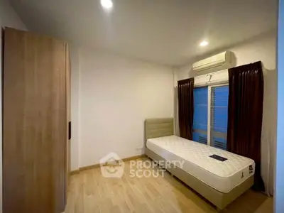 Cozy bedroom with single bed, wooden wardrobe, and air conditioning in modern apartment.