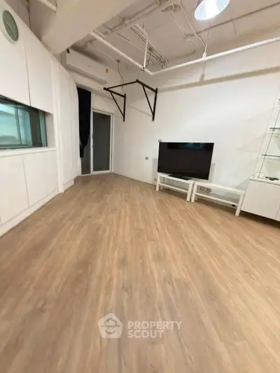 Spacious living room with modern flooring and TV setup, ideal for entertainment and relaxation.