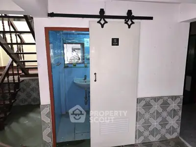 Compact bathroom with sliding door under staircase in residential property