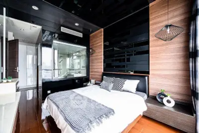 Luxurious modern bedroom with sleek design and stylish decor, featuring a glass wall overlooking a chic bathroom.