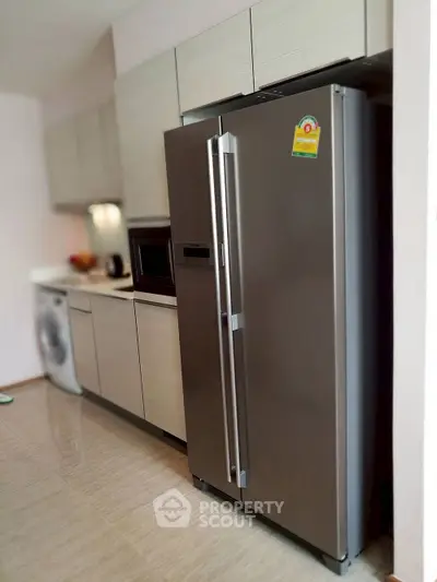 Modern kitchen with sleek appliances including a stainless steel fridge and washing machine.