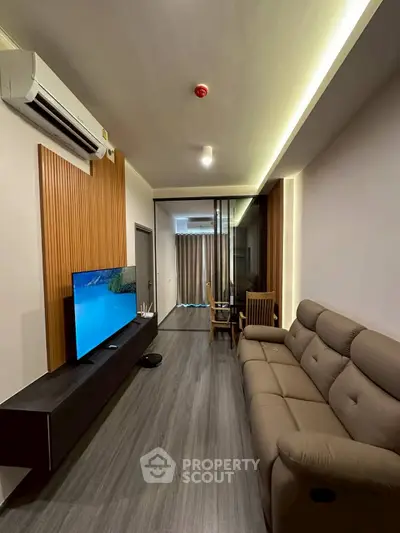Modern living room with sleek design, featuring a comfortable sofa and large TV, perfect for relaxation.