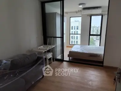 Modern apartment with glass partition, cozy living area, and bright bedroom view.