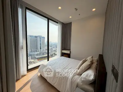 Modern bedroom with stunning city view from floor-to-ceiling windows in high-rise apartment.