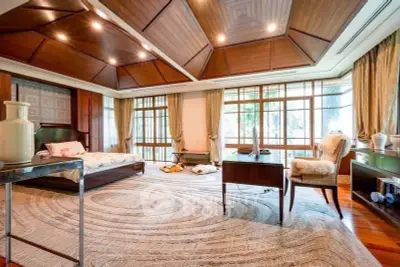Luxurious bedroom with wooden ceiling and large windows offering serene garden views.