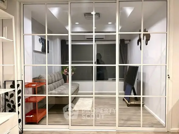 Modern living room with glass partition, stylish decor, and cozy seating area.