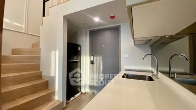 Modern kitchen with sleek design and wooden staircase in stylish apartment