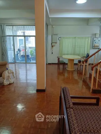 Spacious living room with parquet flooring and large windows for natural light.