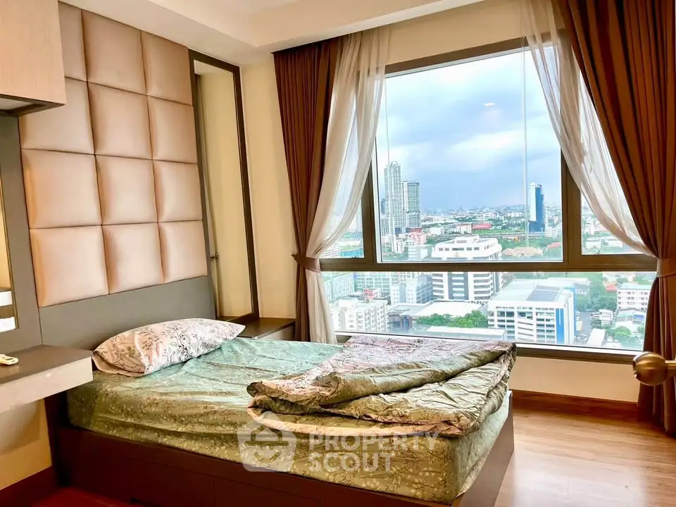 Cozy bedroom with stunning city view from large window, featuring elegant curtains and modern decor.