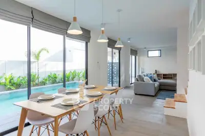 Modern open-plan living and dining area with pool view and stylish decor.