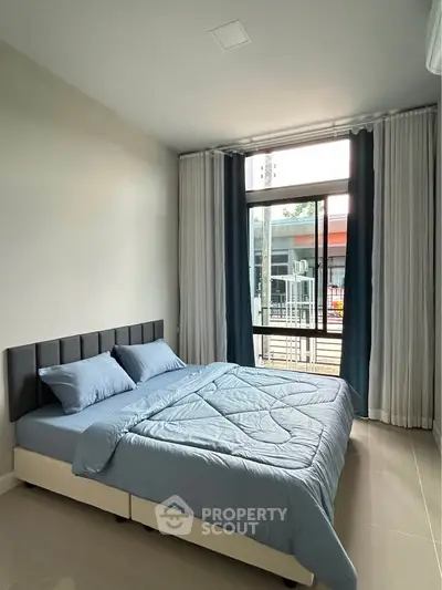 Modern bedroom with large window and stylish decor in a contemporary apartment.