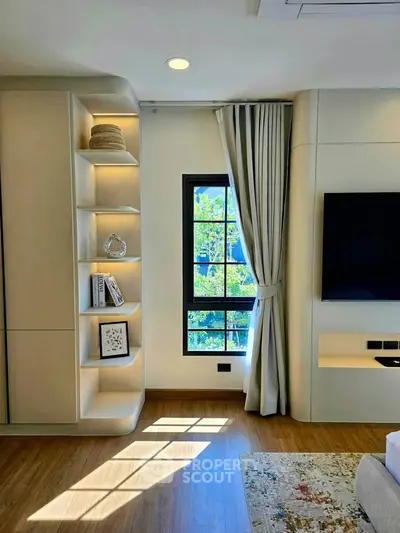 Modern living room with built-in shelves, large window, and wall-mounted TV