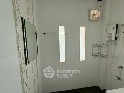 Modern bathroom with sleek white tiles and ventilation fan