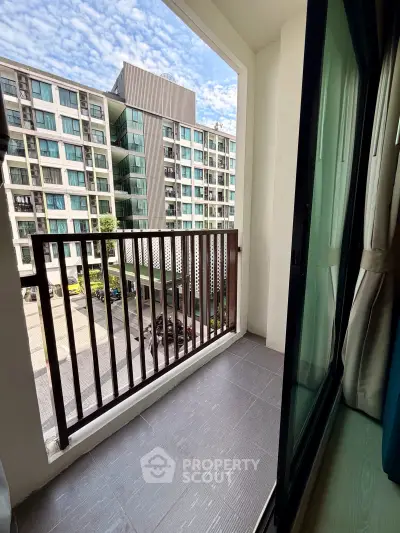 Charming balcony view in modern apartment complex with sleek design and ample natural light.
