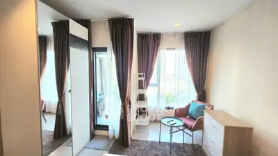 Bright bedroom with large windows, modern furniture, and city view, perfect for urban living.