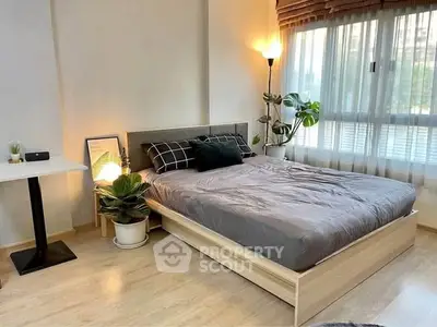 Cozy bedroom with modern decor, large window, and stylish plants enhancing the serene ambiance.