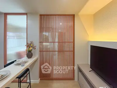 Modern living room with stylish decor and TV unit, featuring a sleek partition and elegant lighting.