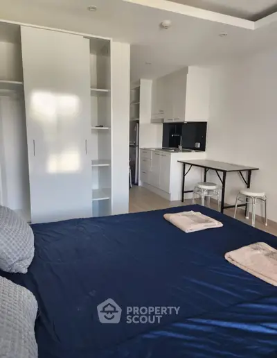 Modern studio apartment with cozy bed and compact kitchen
