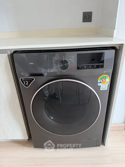 Modern washing machine in sleek kitchen setting with light wood cabinetry and neutral tones.