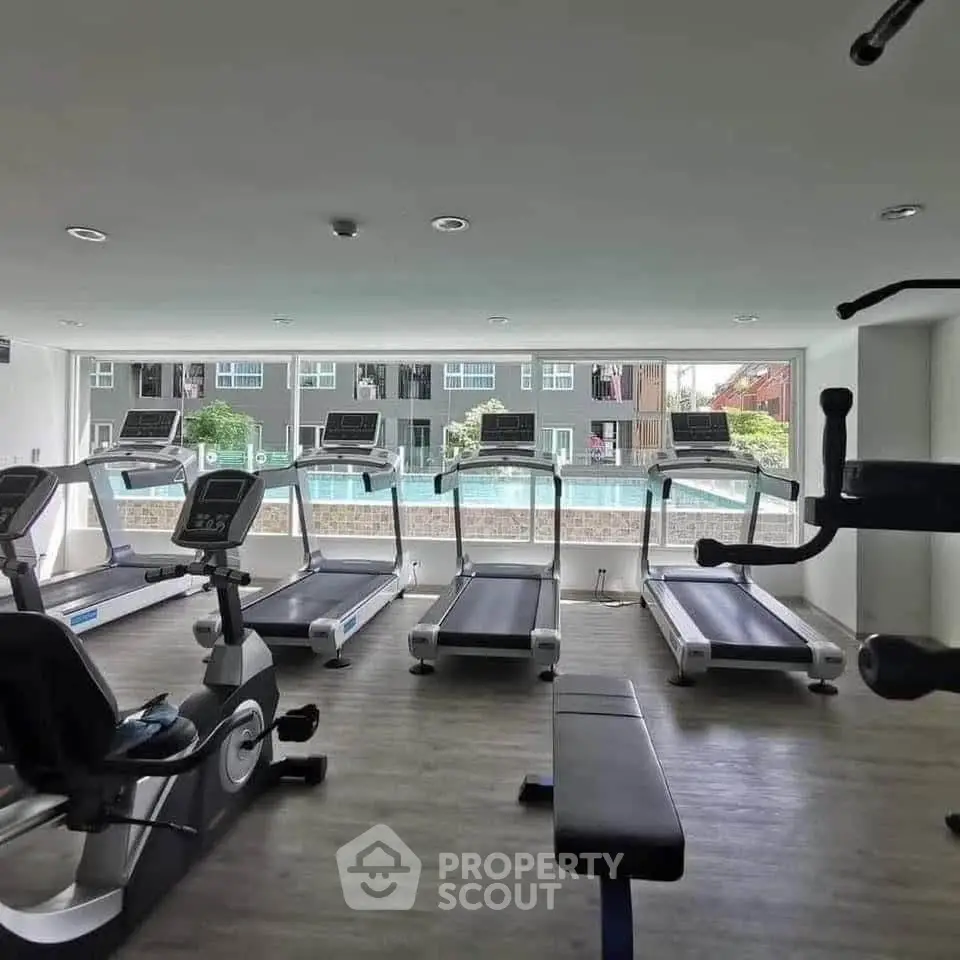 Modern gym with treadmills and exercise equipment overlooking pool view