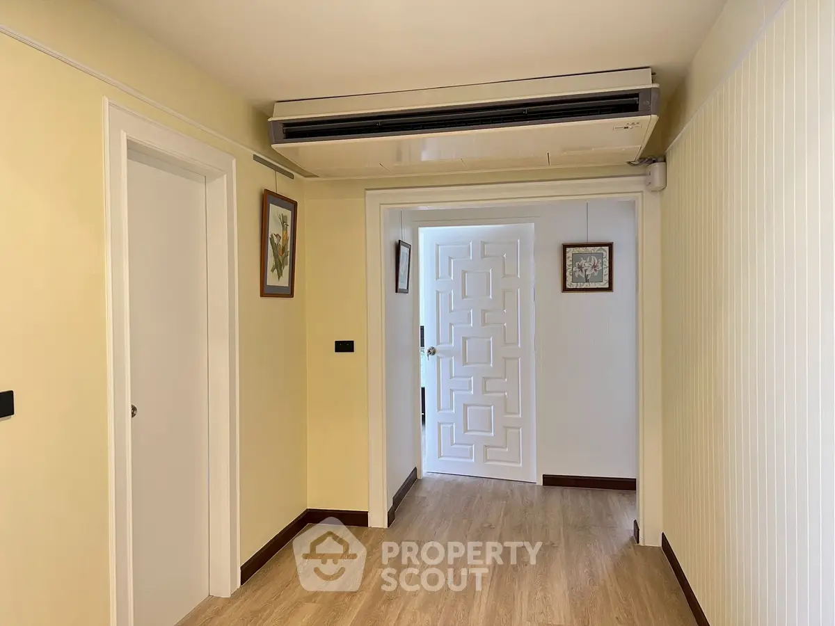 Spacious hallway with elegant wooden flooring and modern air conditioning unit.
