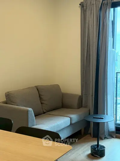 Cozy living room with a grey sofa and city view from window.