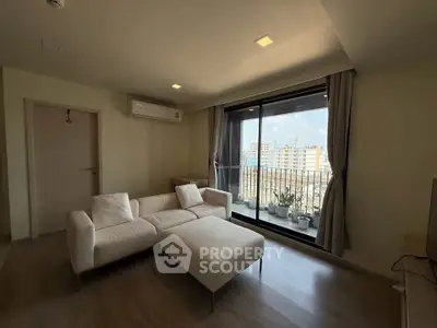 Modern living room with large window and city view, featuring cozy white sofa and elegant decor.