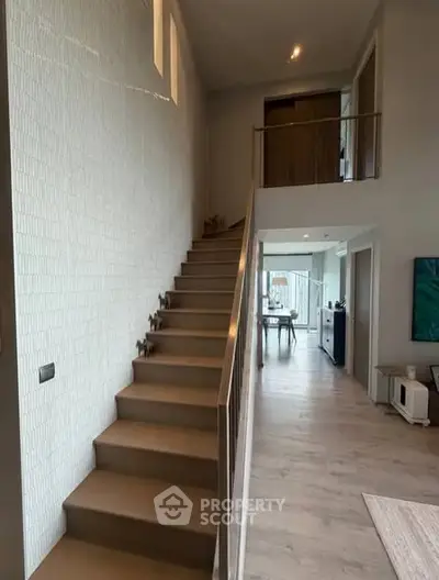 Modern duplex interior with stylish staircase and open living area, showcasing contemporary design and natural light.