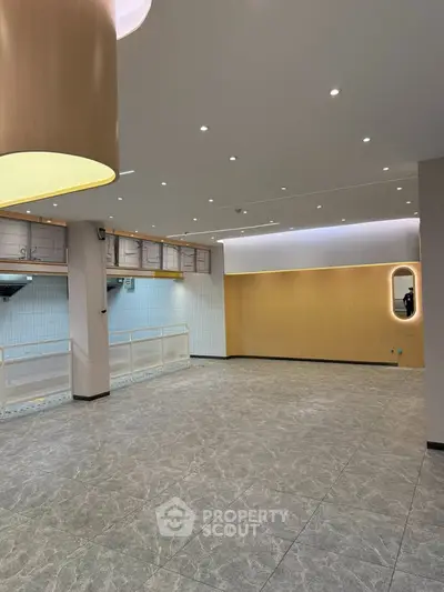 Spacious modern interior with elegant lighting and tiled flooring, perfect for versatile use.