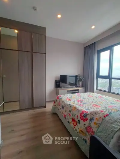 Cozy bedroom with large window and modern decor in high-rise apartment