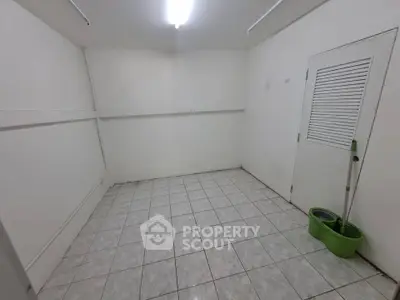 Spacious tiled storage room with white walls and ceiling light, ideal for organizing essentials.