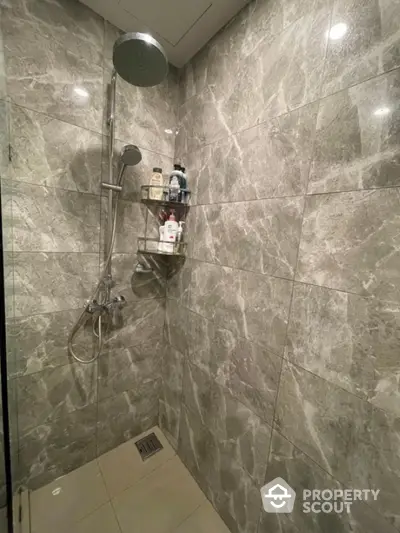 Luxurious marble-tiled shower with modern fixtures and built-in shelf.