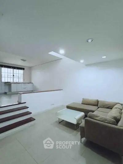 Spacious living room with modern sectional sofa and open kitchen layout.